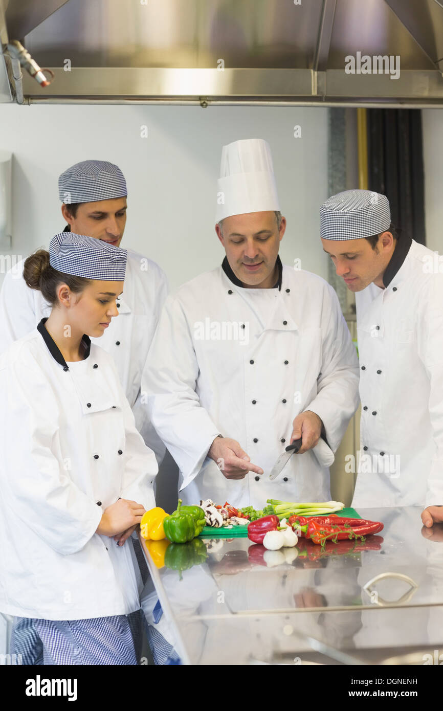 Smiling head chef teaching how to chop vegetables Stock Photo
