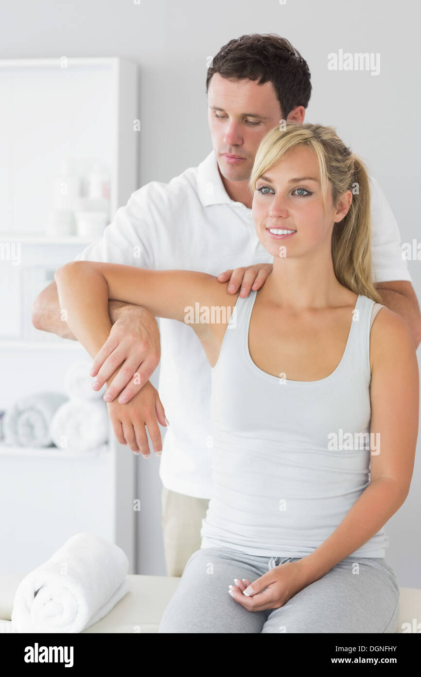 Good looking physiotherapist controlling patients arm Stock Photo