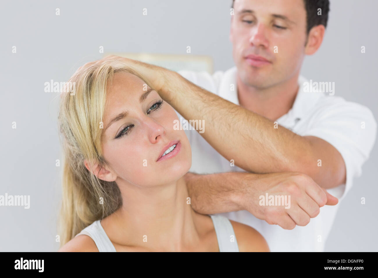 Good looking physiotherapist massaging patients neck with elbow Stock Photo