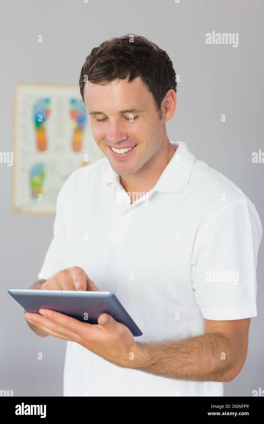 Handsome smiling physiotherapist using tablet Stock Photo