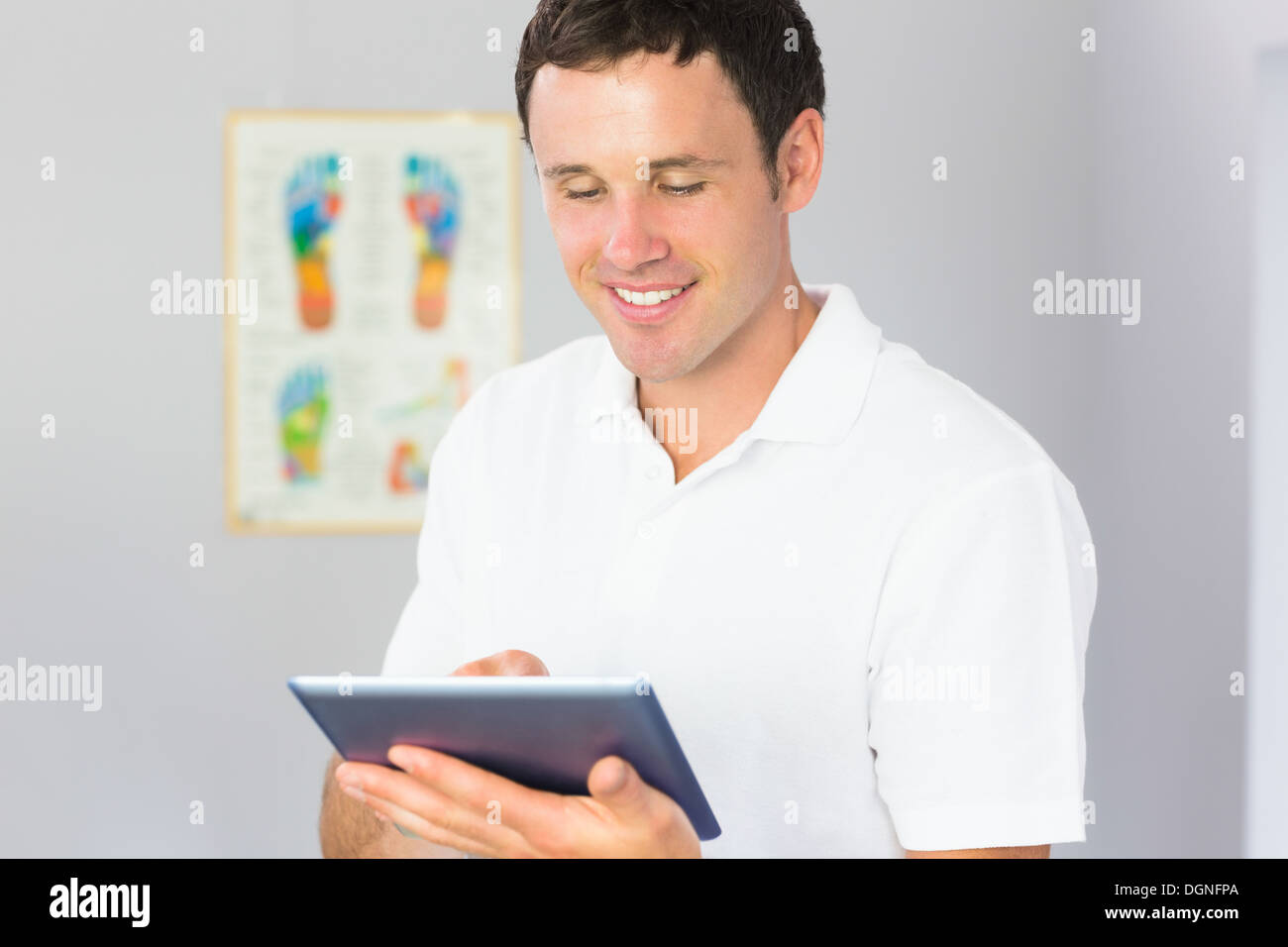 Handsome cheerful physiotherapist using tablet Stock Photo