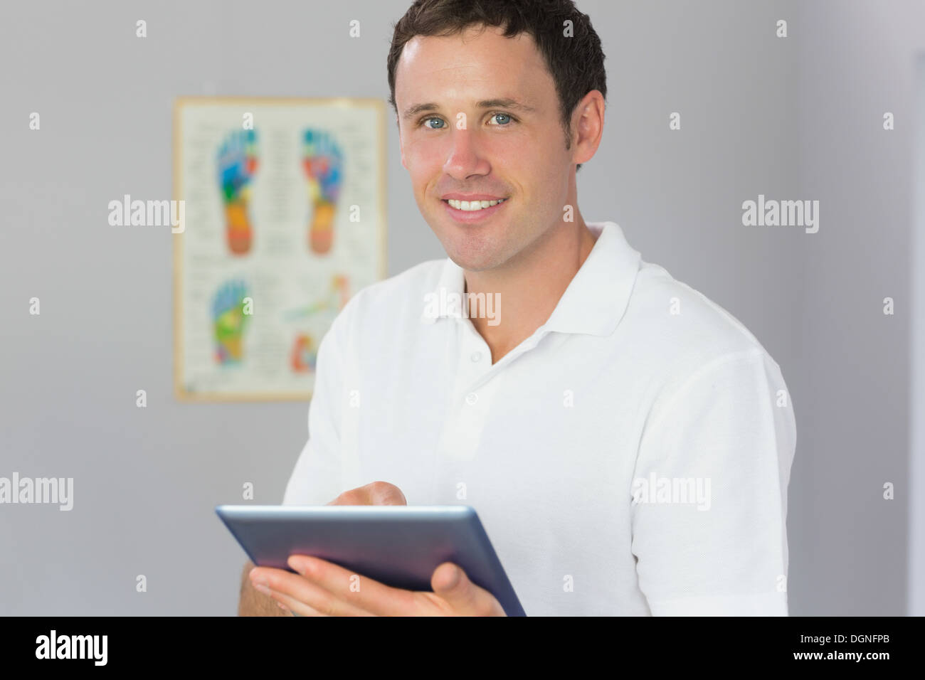 Handsome cheerful physiotherapist holding tablet Stock Photo