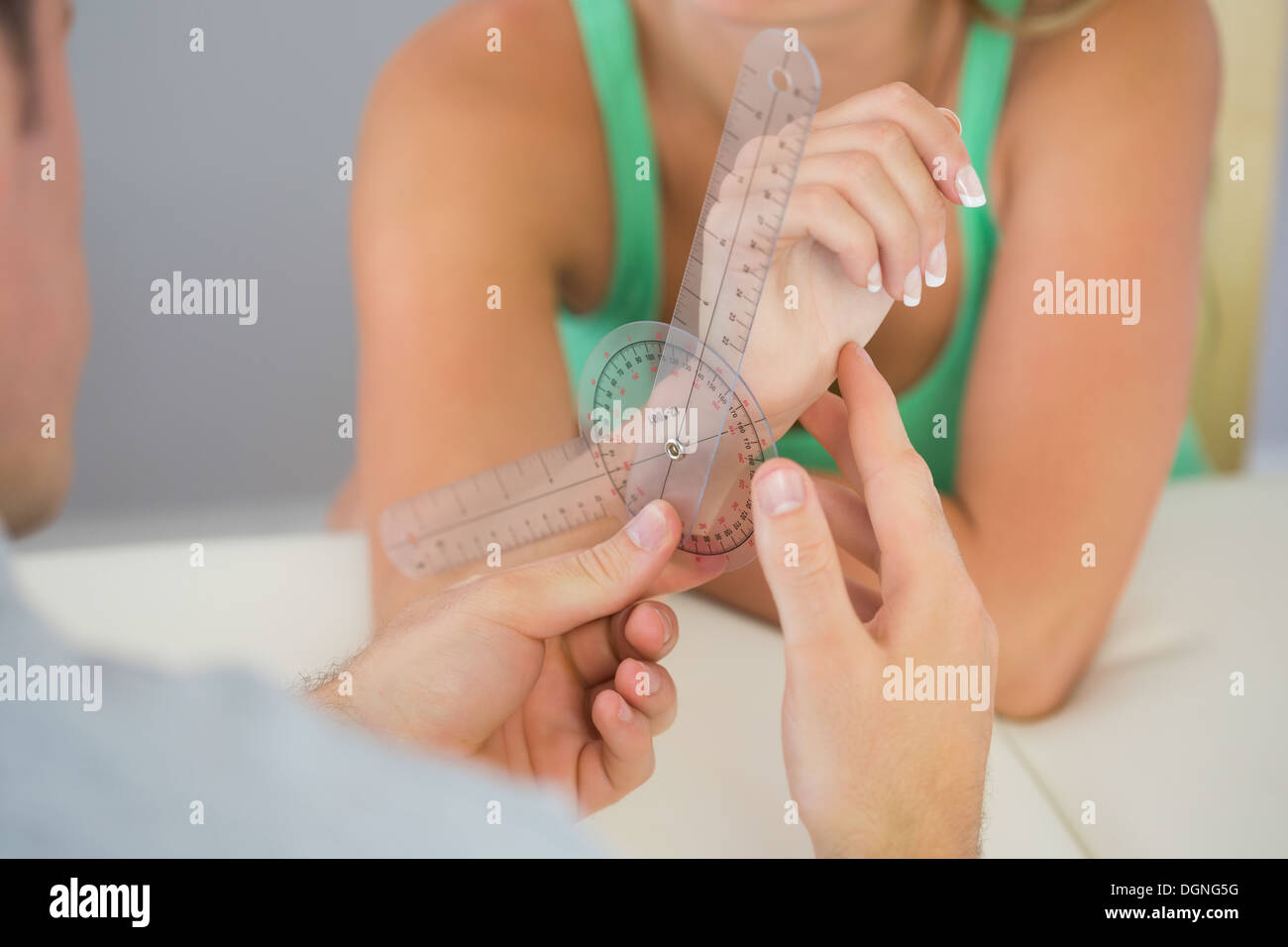 Physiotherapist examining patients wrist with goniometer Stock Photo