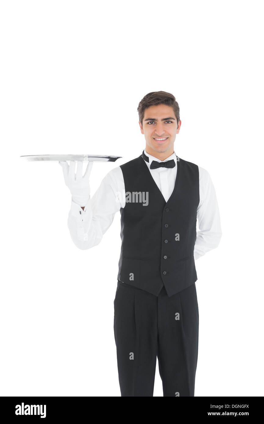 Cheerful young waiter showing an empty silver tray Stock Photo