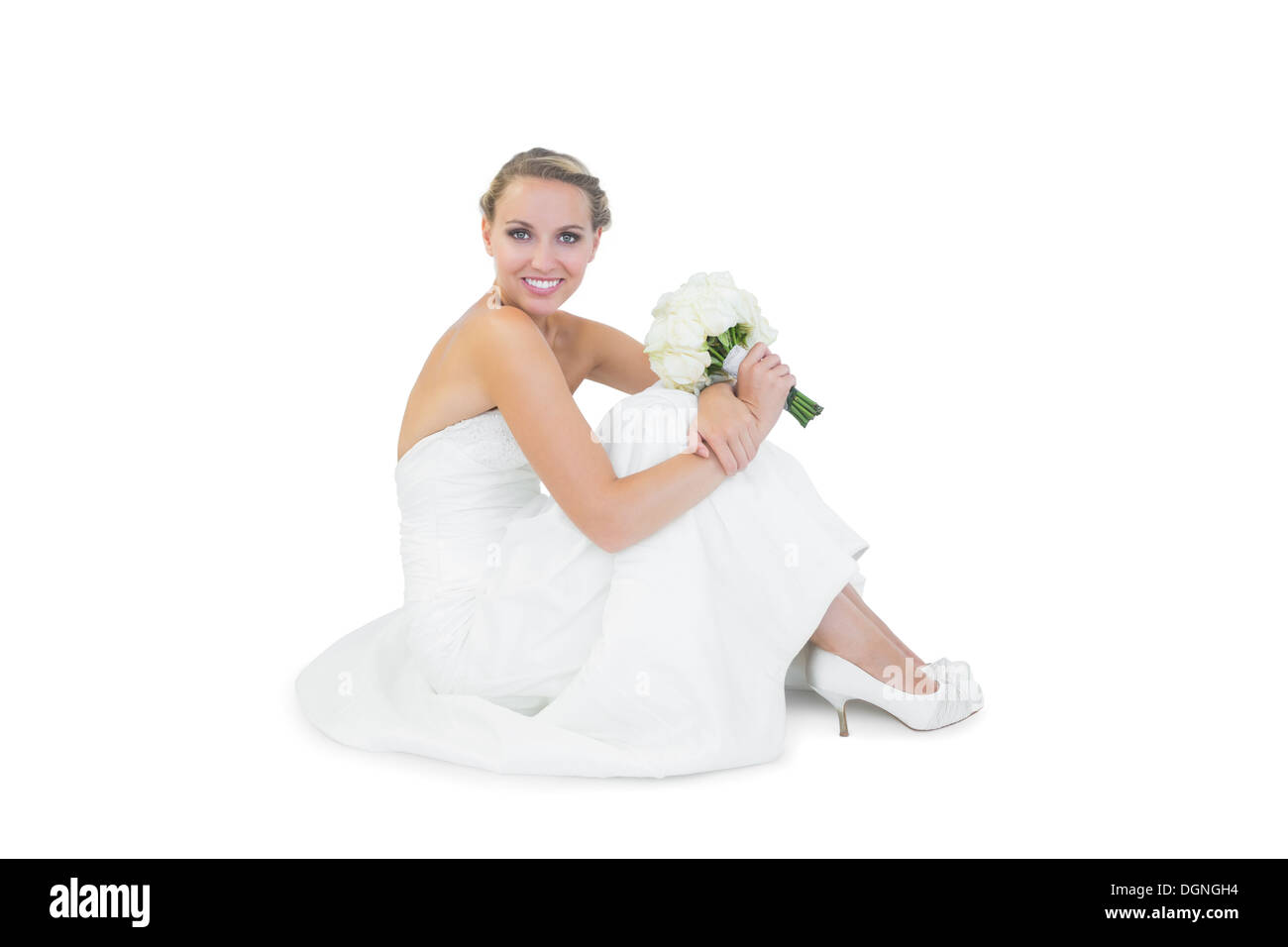 Pretty blonde bride sitting on floor holding a bouquet Stock Photo
