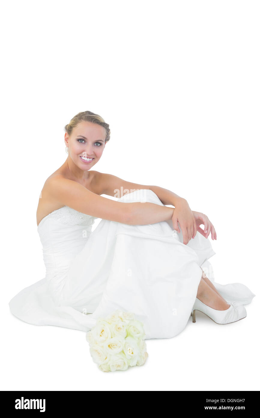 Young blonde bride sitting next to her bouquet Stock Photo
