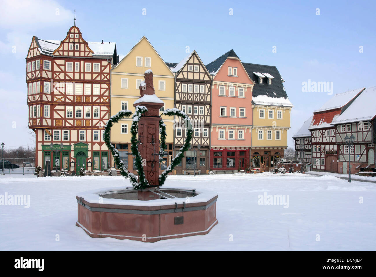 Historic row of houses on market square, market well, snow, winter in Hessenpark, Neu-Anspach, Taunus, Hesse Stock Photo