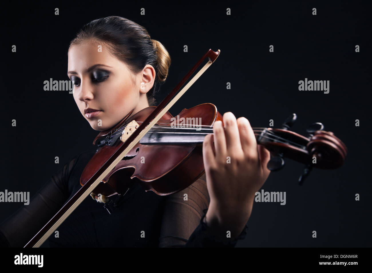 Beautiful young woman playing violin over black Stock Photo - Alamy