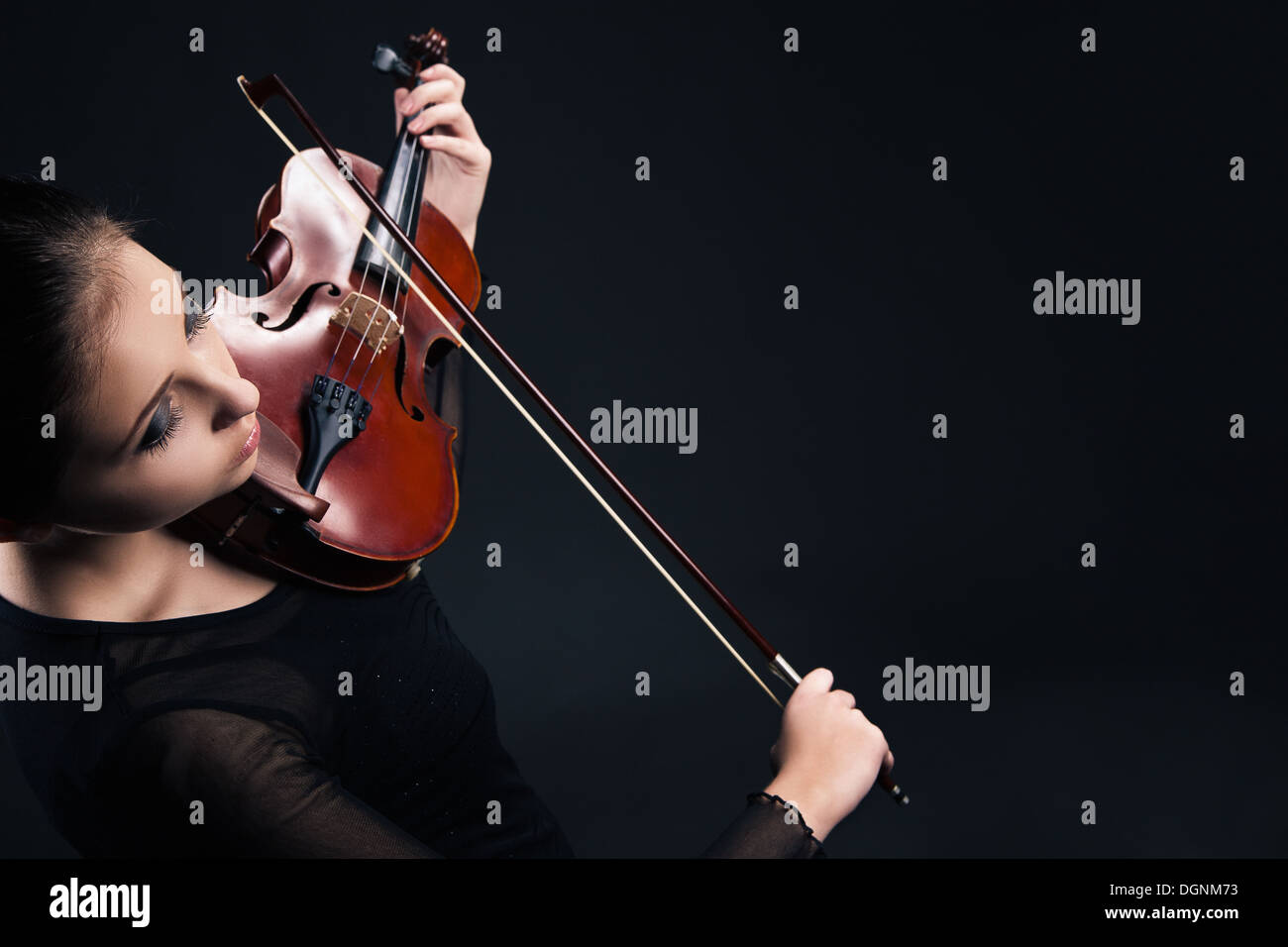 Beautiful young woman playing violin over black Stock Photo - Alamy