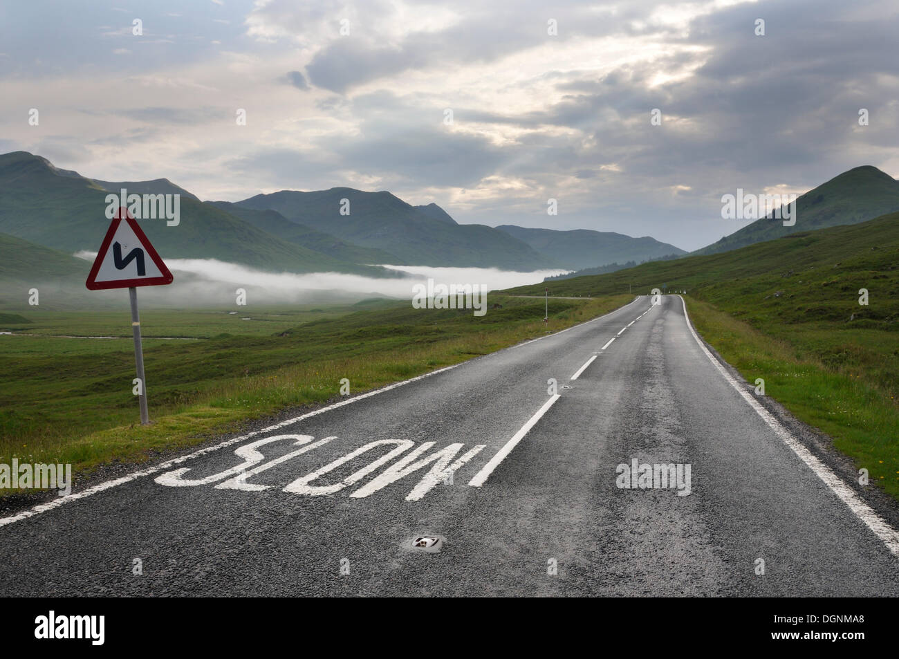 Driving on the left side of the road, with the marking 'Slow' on the road in the Highlands, Scotland, United Kingdom Stock Photo