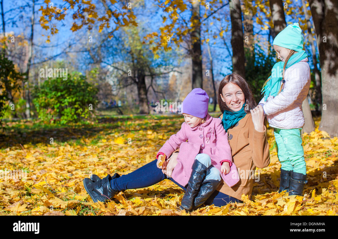 Two adorable girls with his young mom in the park on a sunny autumn day ...
