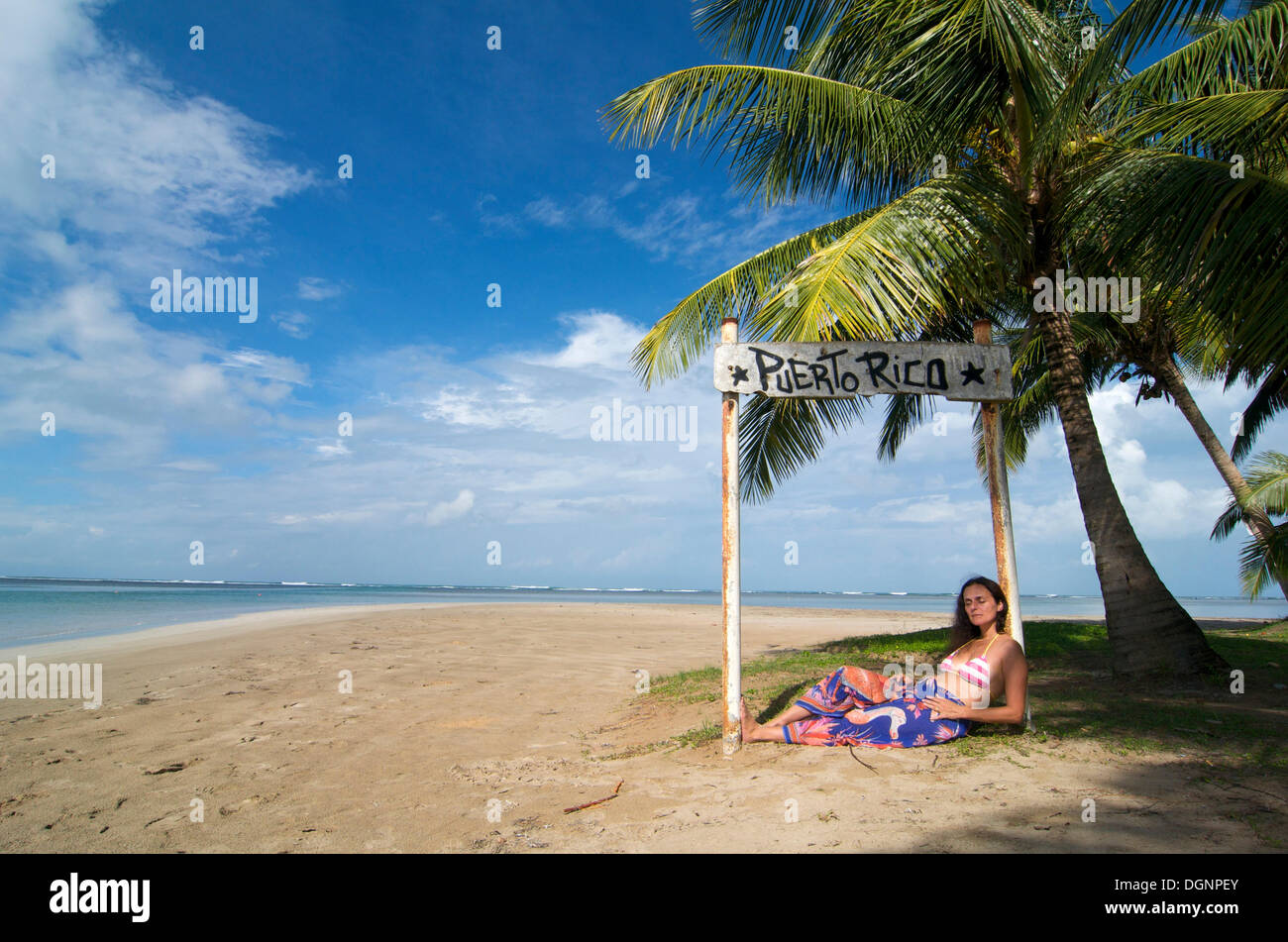 Tourist lying under a sign with the words Puerto Rico, Luquillo Beach, Puerto Rico, Caribbean Stock Photo