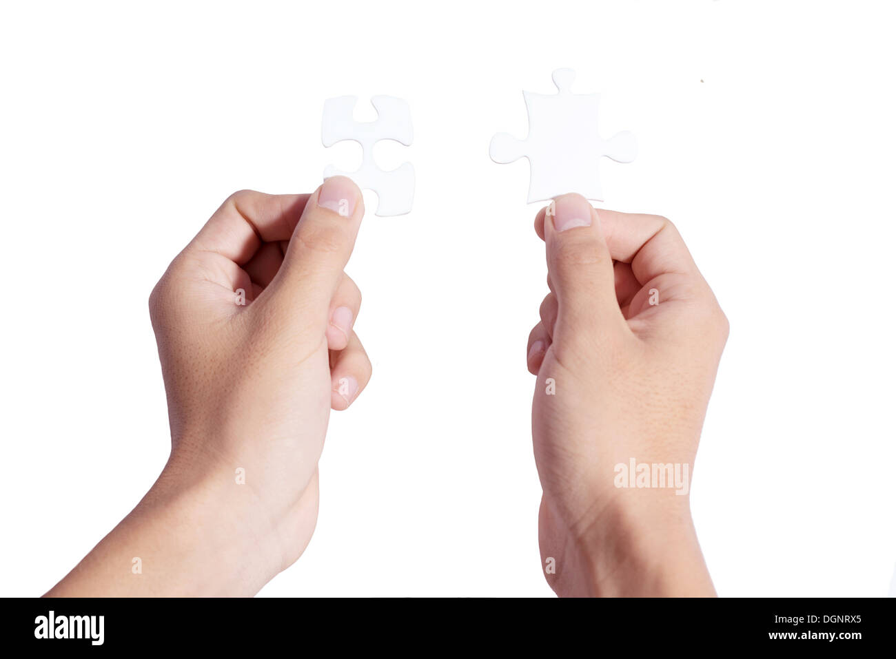 Two hands holding puzzle pieces and connecting them Stock Photo