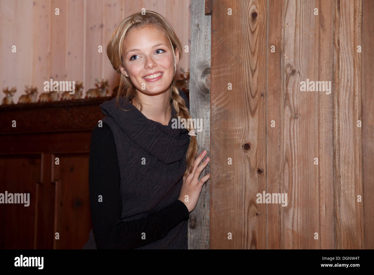 Smiling young woman leaning against a old door Stock Photo