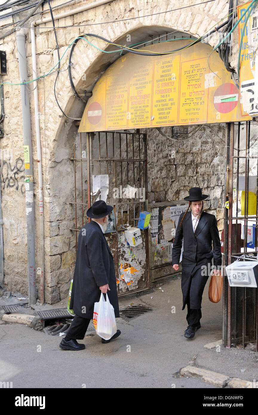 Sign prohibiting the entry of non-Orthodox Jews in a residential housing estate, with two Orthodox Jews passing through the Stock Photo
