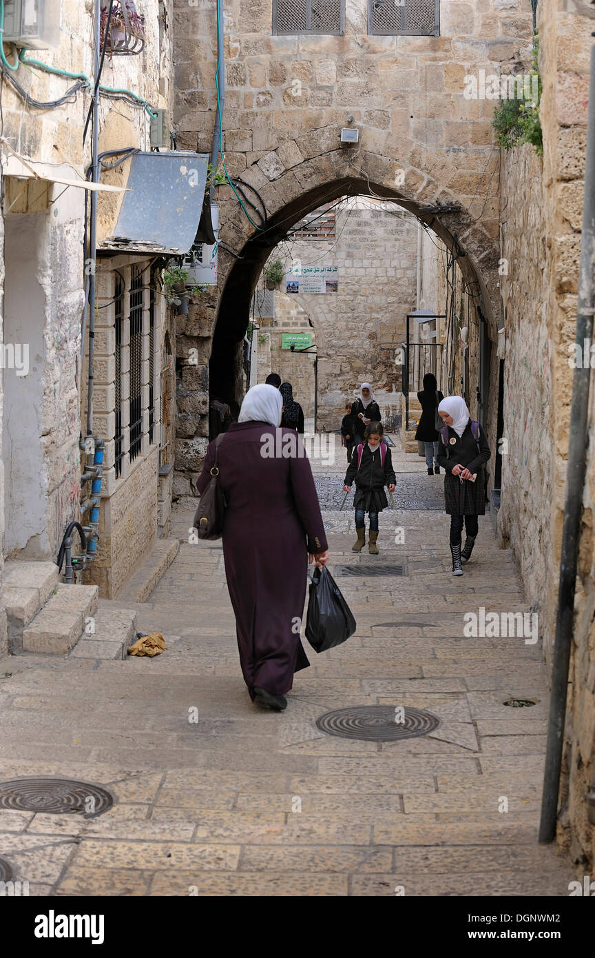 Palestinian woman wearing a headscarf and students walking on an alley in the Arab district, Jerusalem, Israel, Asia Stock Photo