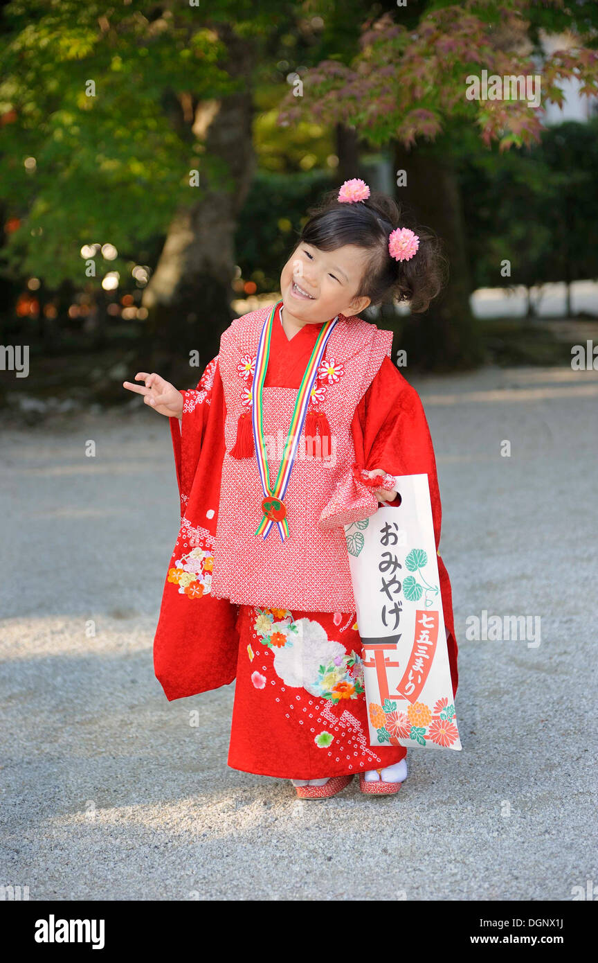 Shichi-go-san, Seven-Five-Three festival, girl in a red kimono holding a long bag with candy canes, Chitose-ame, standing on the Stock Photo
