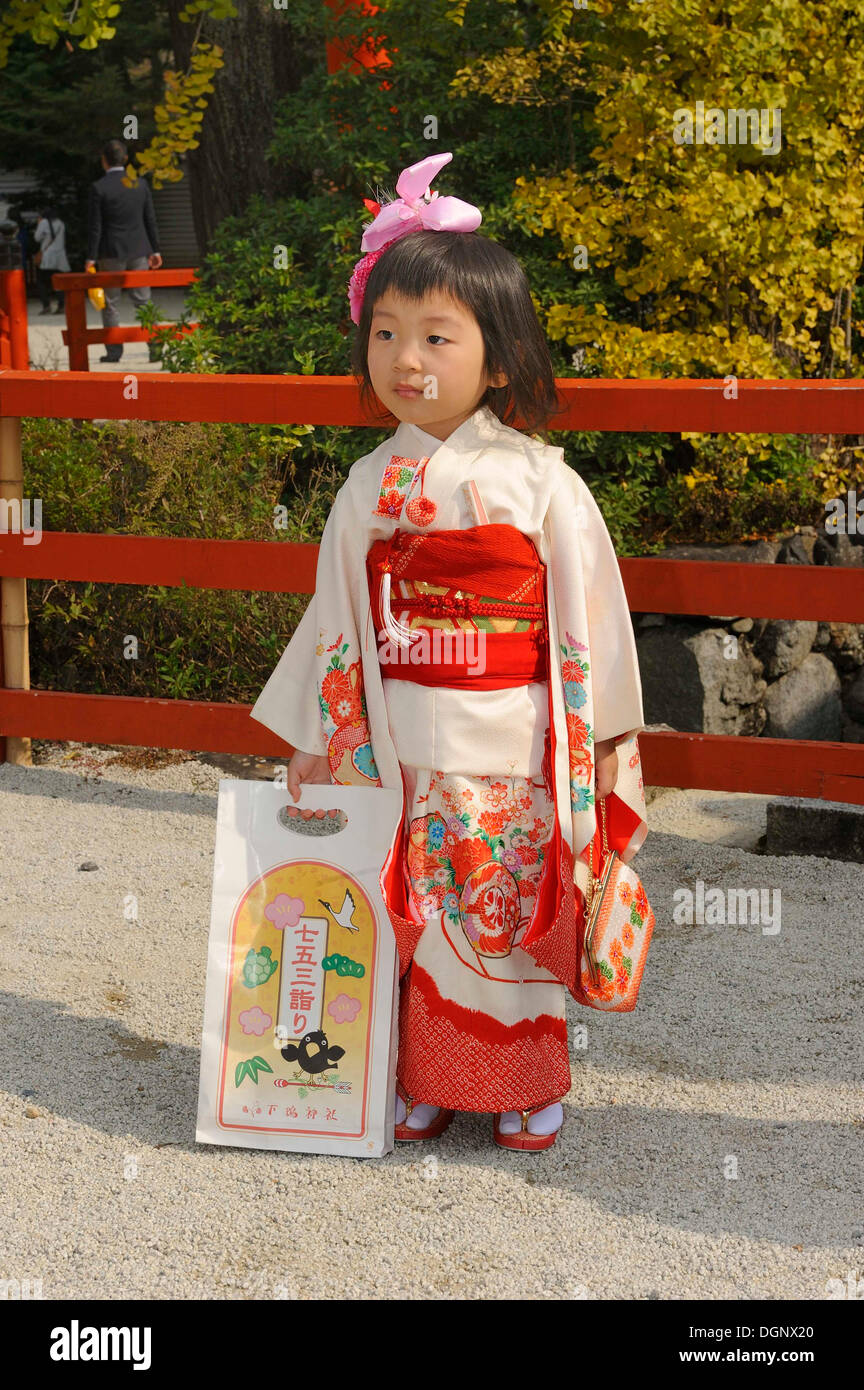 Girl wearing a festive kimono at the Shichi-go-san festival or Seven-Five-Three festival, she is holding a typical Chitose-ame Stock Photo