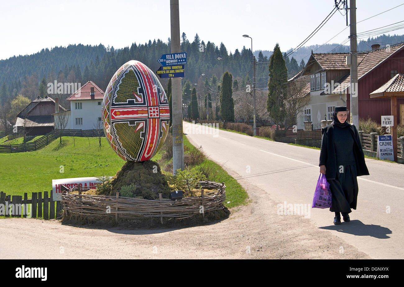 Nun, oversized Easter egg as a sign to the Moldova convent, Vorone&#355; Monastery, Eastern Carpathians, Romania, Europe Stock Photo