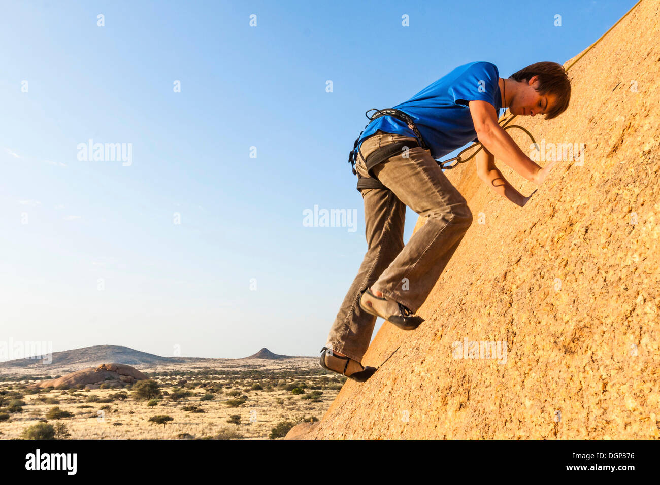 Young man climbing at Bogenfels, Spitzkoppe area, Damaraland, Namibia, Africa Stock Photo