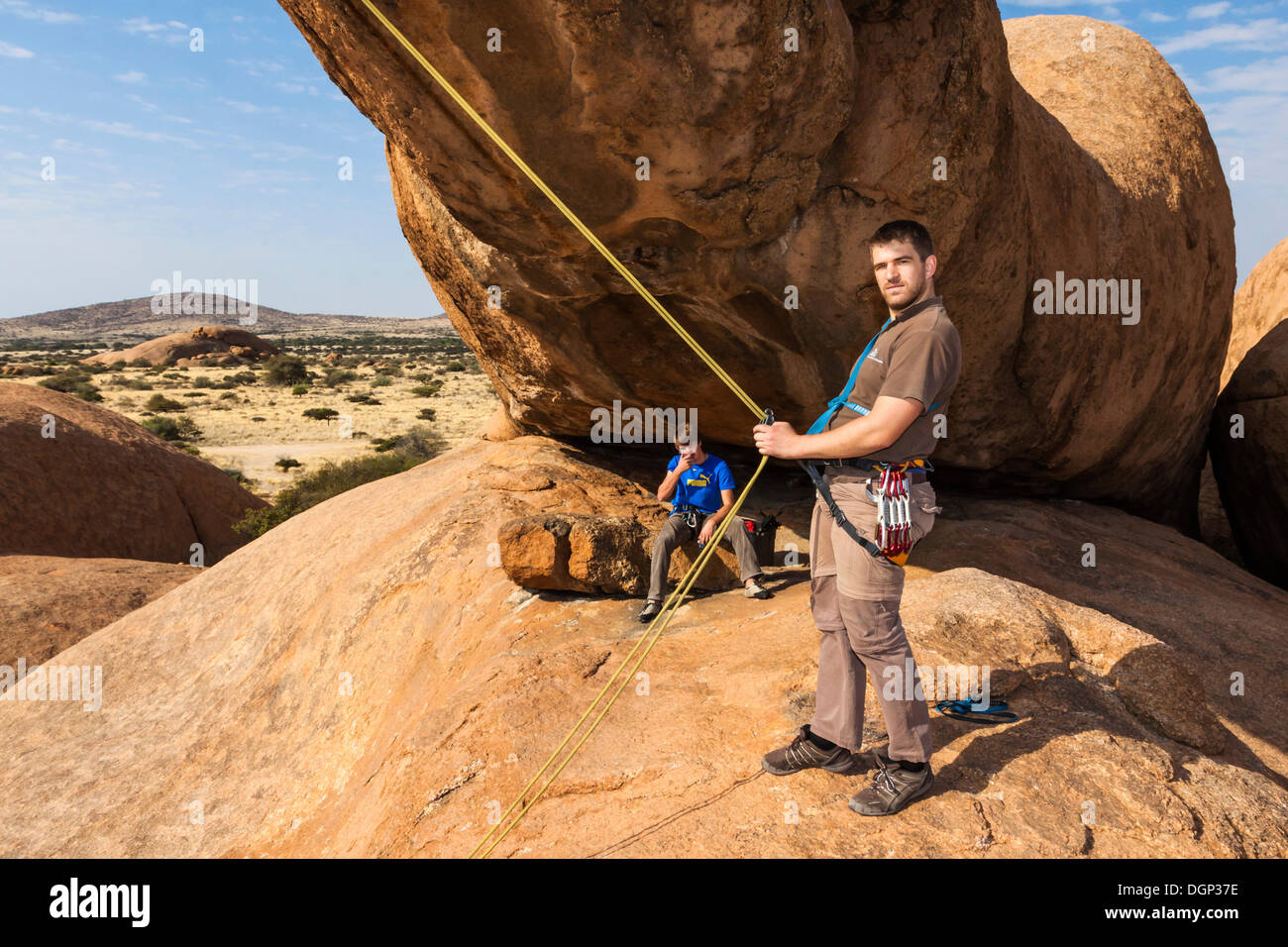 Young man hanging in a climbing rope, Bogenfels, Spitzkoppe area, Namibia, Africa Stock Photo