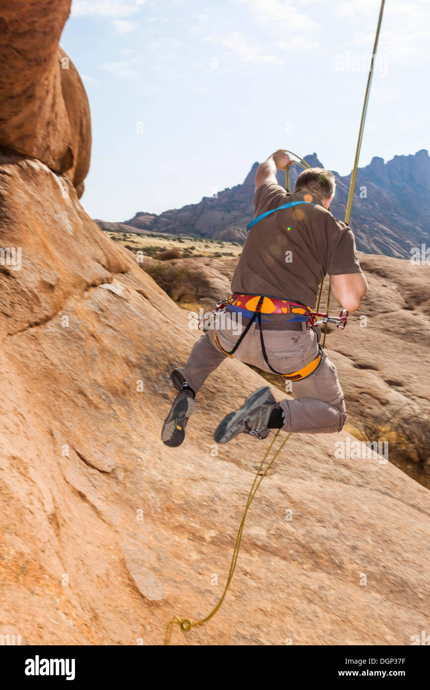 Young man hanging from a climbing rope, Bogenfels, Spitzkoppe area, Namibia, Africa Stock Photo