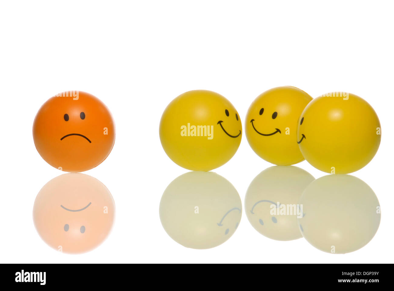 A frowning smiley, frownie standing apart from a group of smileys, symbolic image for bullying Stock Photo