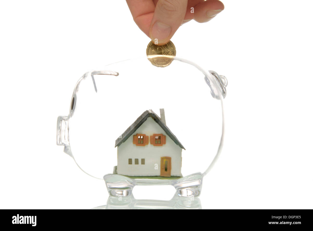 Hand putting coin into piggy bank with a house, symbolic image for ...