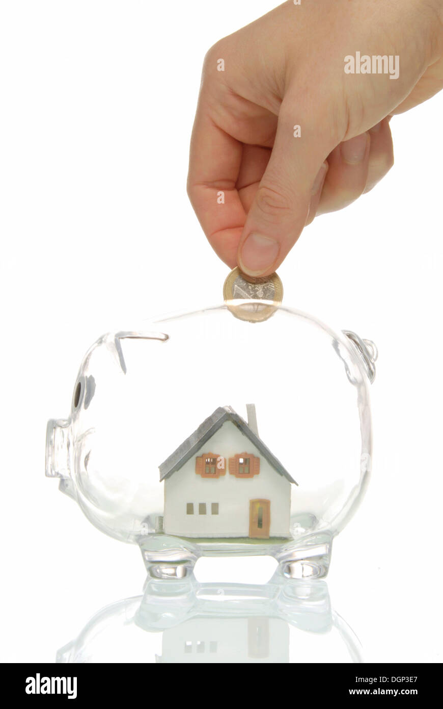 Hand putting coin into piggy bank with a house, symbolic image for ...