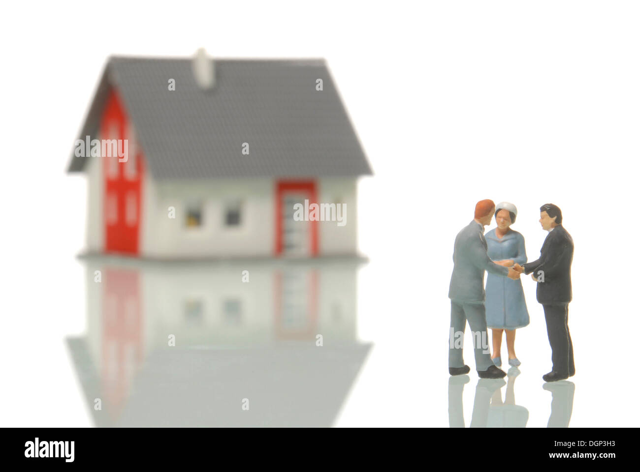 Couple buying a house from a realtor, figurines, a blurred house in the back, symbolic image for the real estate market Stock Photo