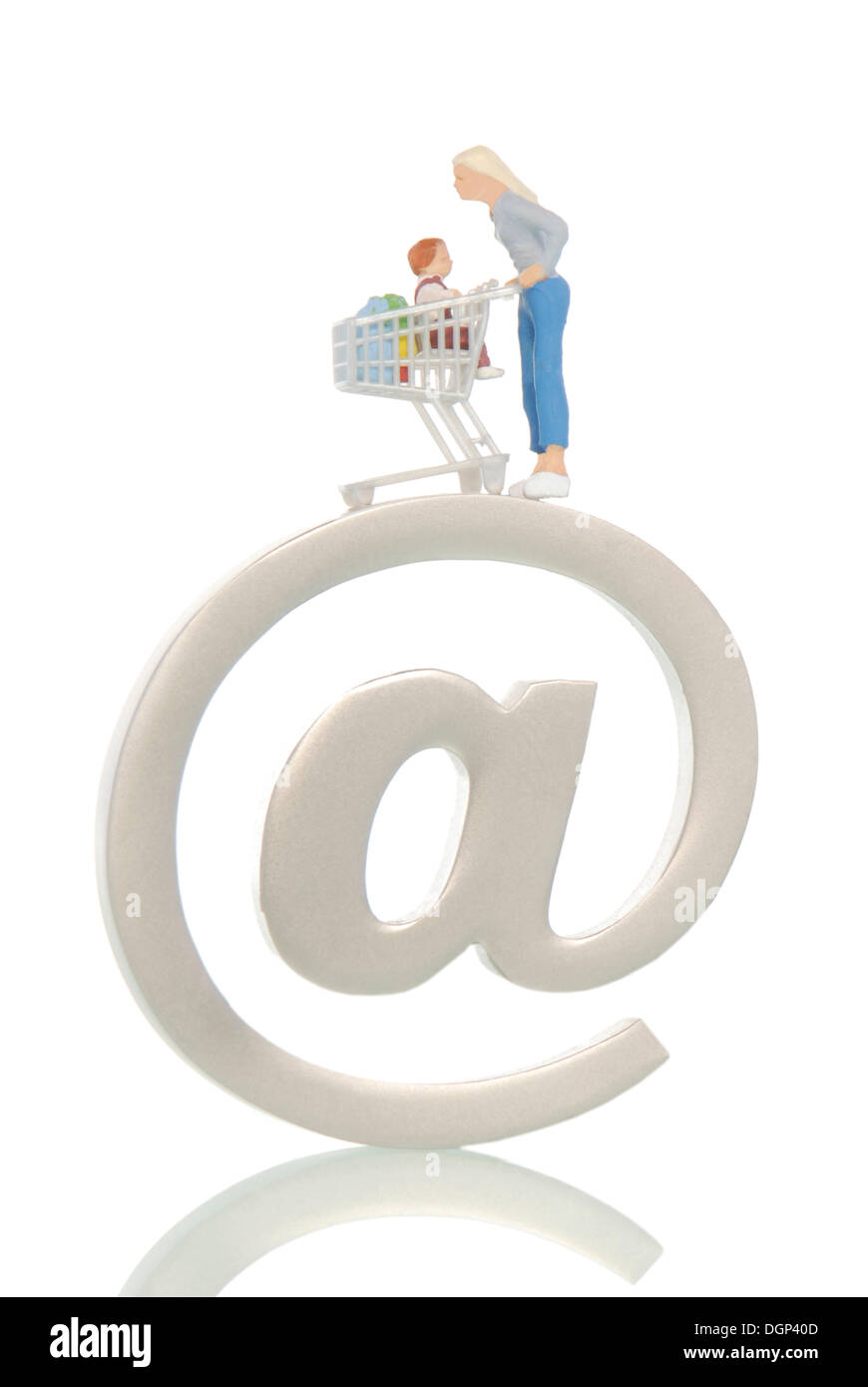 Miniature figures of a woman with a shopping cart and an infant on an at sign, symbolic image for online shopping Stock Photo