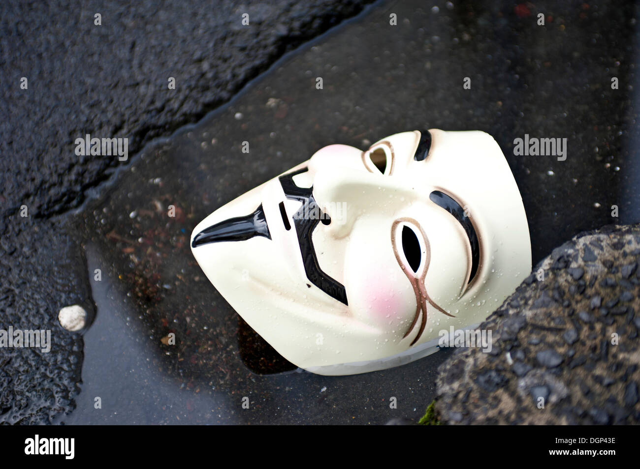 Anonymous mask, Guy Fawkes mask lying discarded on a street, symbolic image Stock Photo