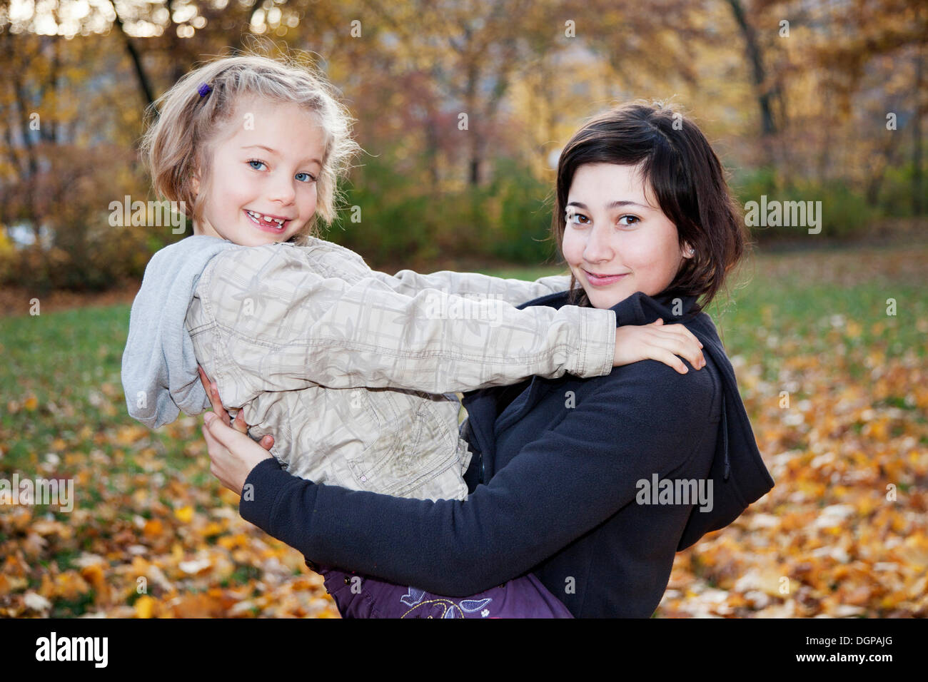 Teenage girl, 14 years, holding girl, 6 years, in her arms Stock Photo