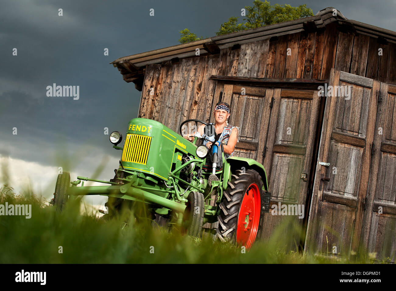 Man with a prosthetic leg driving a vintage tractor Stock Photo