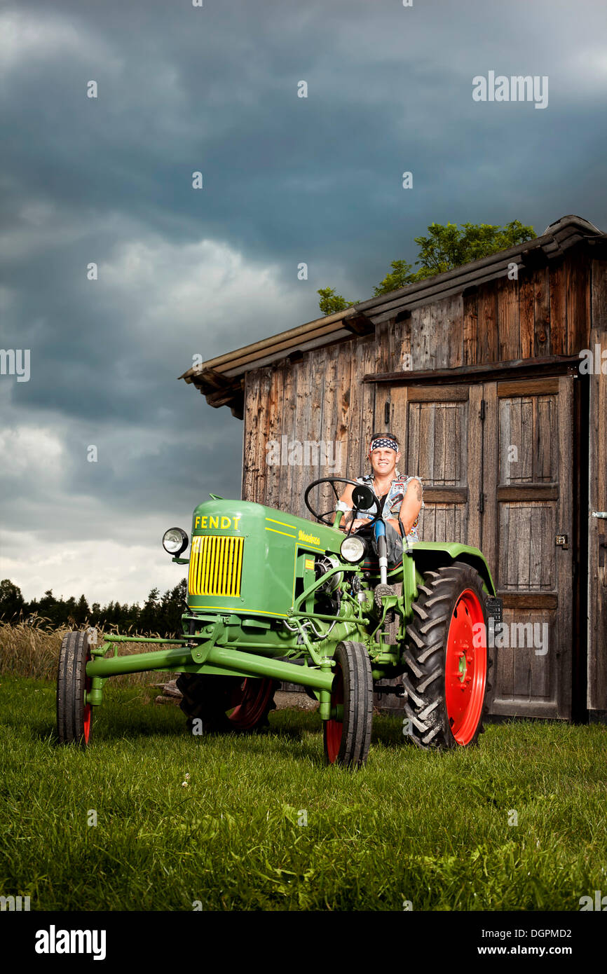 Man with a prosthetic leg driving a vintage tractor Stock Photo