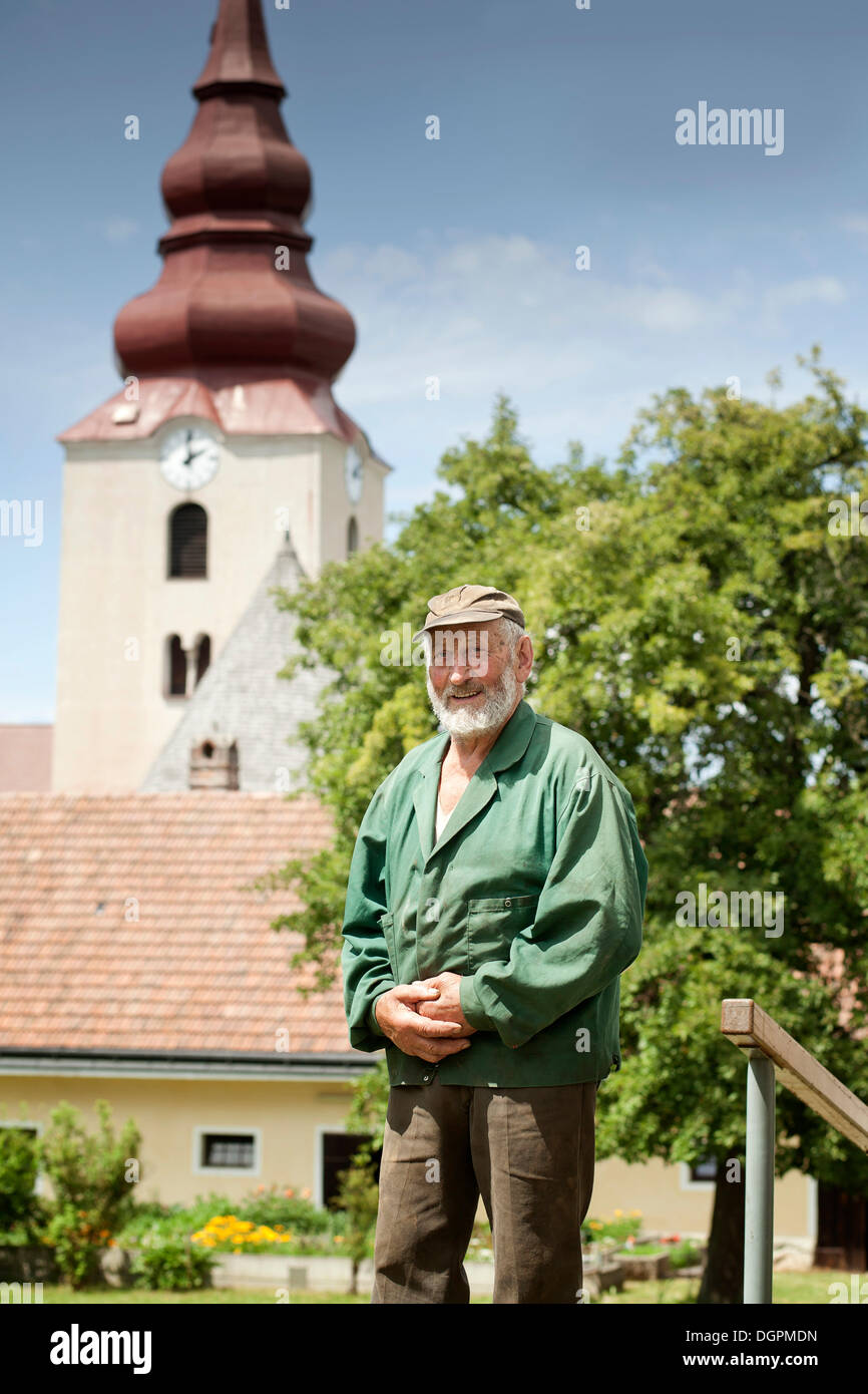 Old man, farmer standing in front of a church Stock Photo