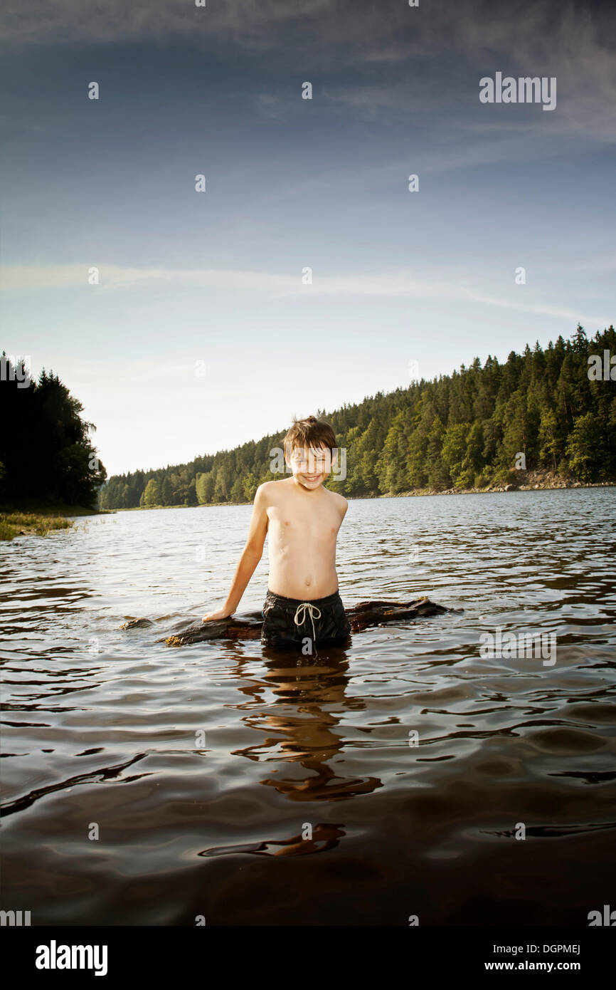 Boy playing with driftwood in a lake Stock Photo