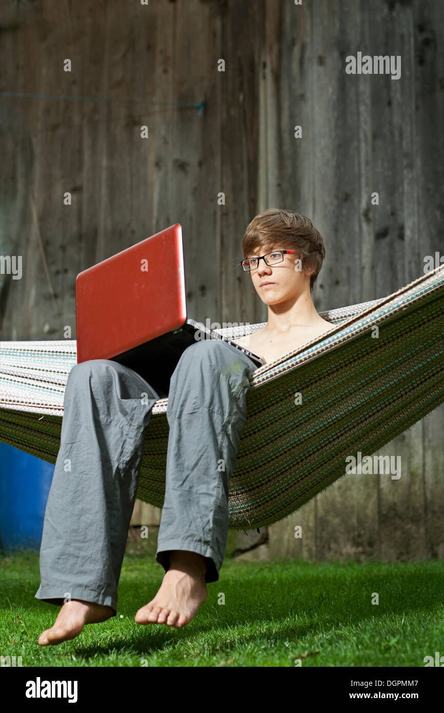 Teenager sitting in a hammock with a laptop Stock Photo Alamy