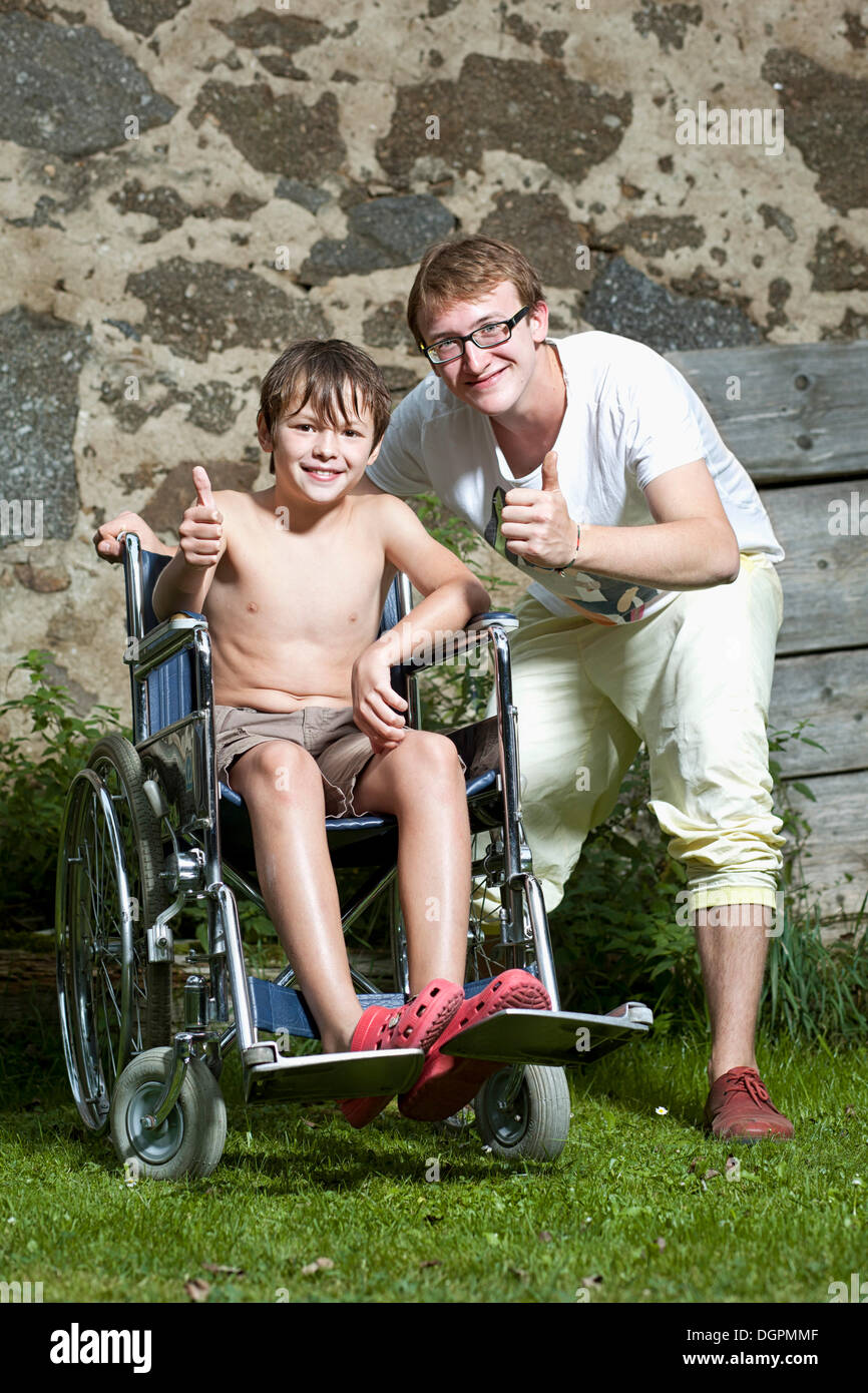 Boy sitting in a wheelchair with his friend standing next to him Stock Photo