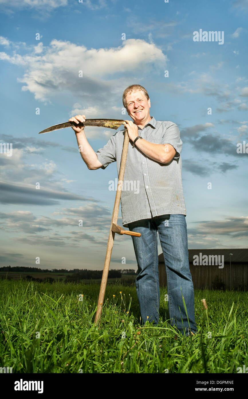 Farmer holding a scythe Stock Photo