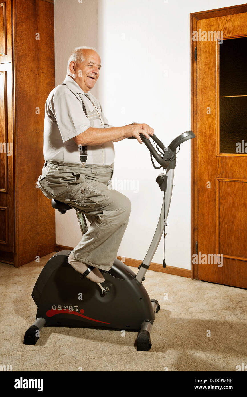 Elderly man sitting on an exercise bike Stock Photo