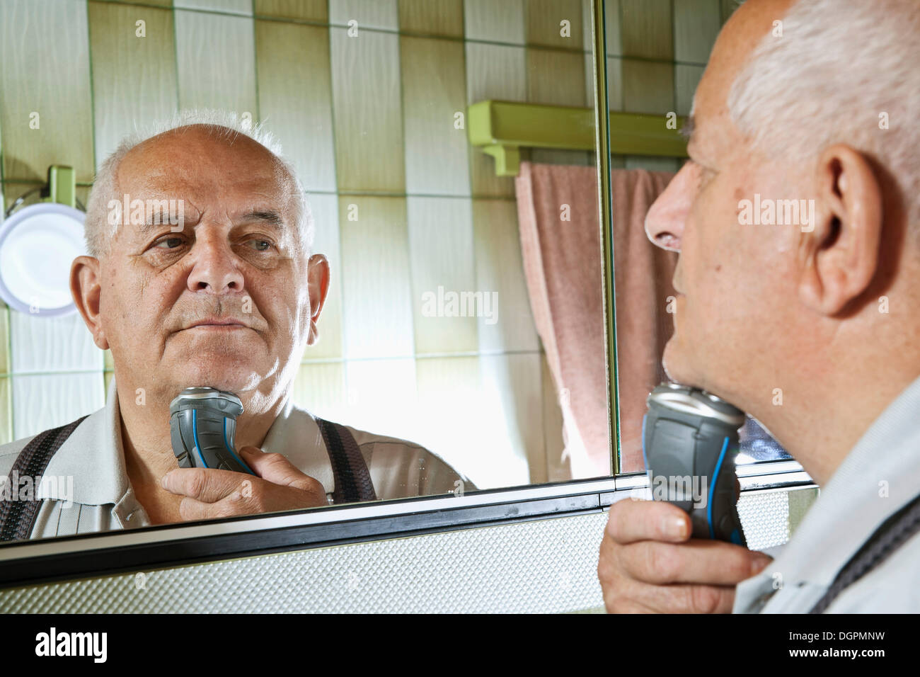 Elderly man using an electric shaver Stock Photo