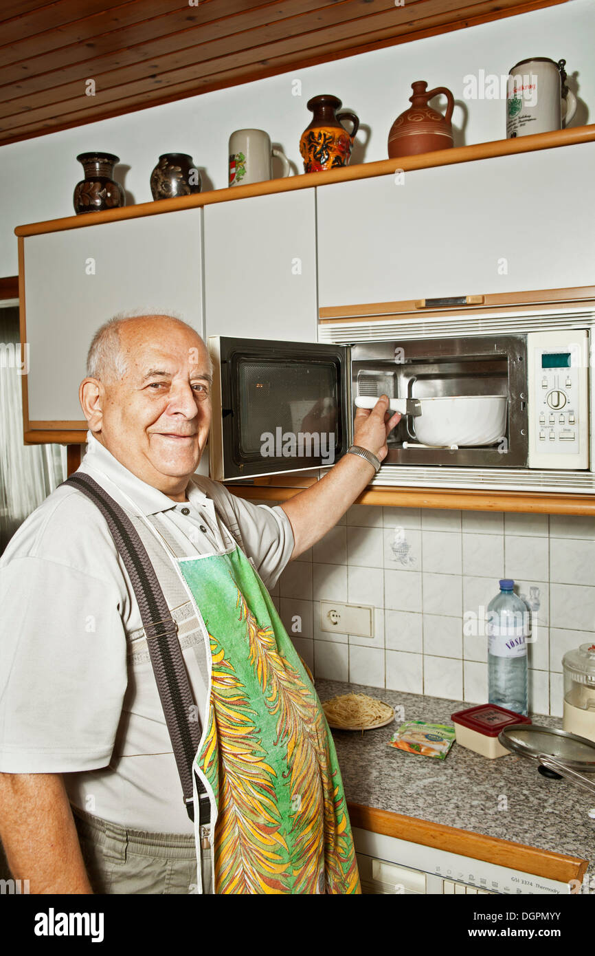 Elderly man cooking with a microwave oven Stock Photo