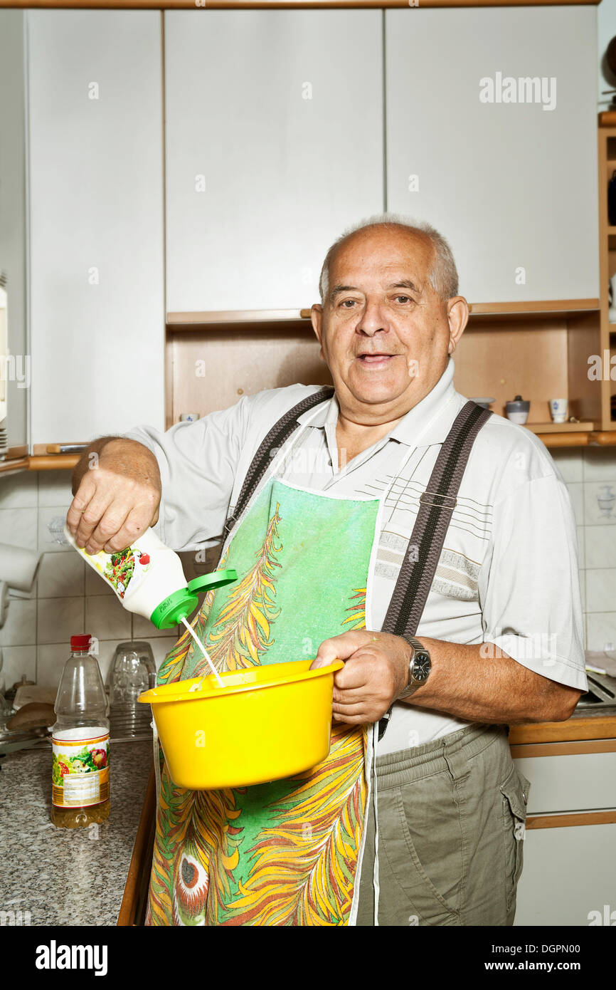 Elderly man holding a salad bowl in a kitchen Stock Photo