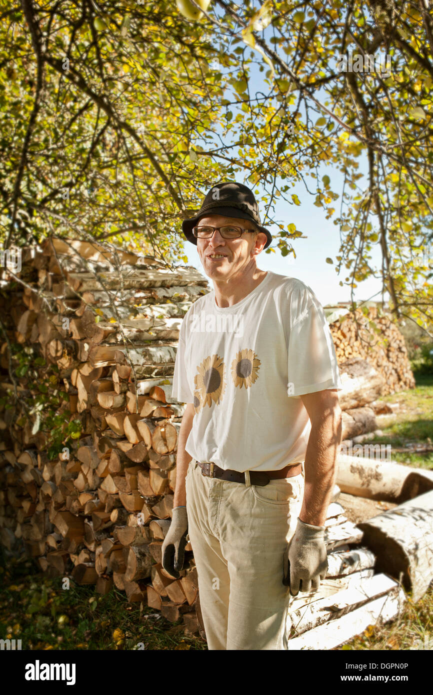 Man in the orchard in front of a wood pile Stock Photo