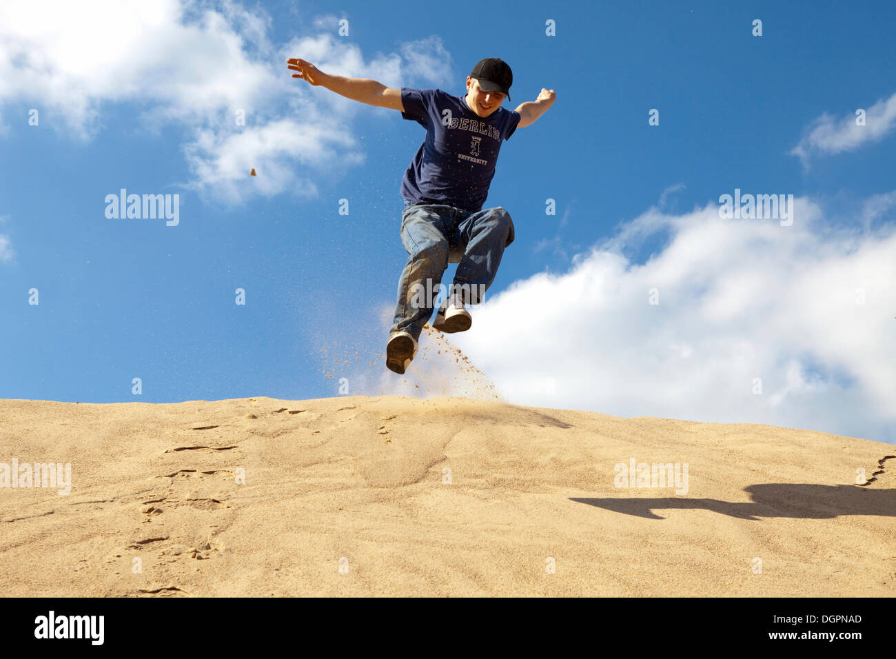 Young man jumping down a sand hill, Oettingen, Bavaria Stock Photo