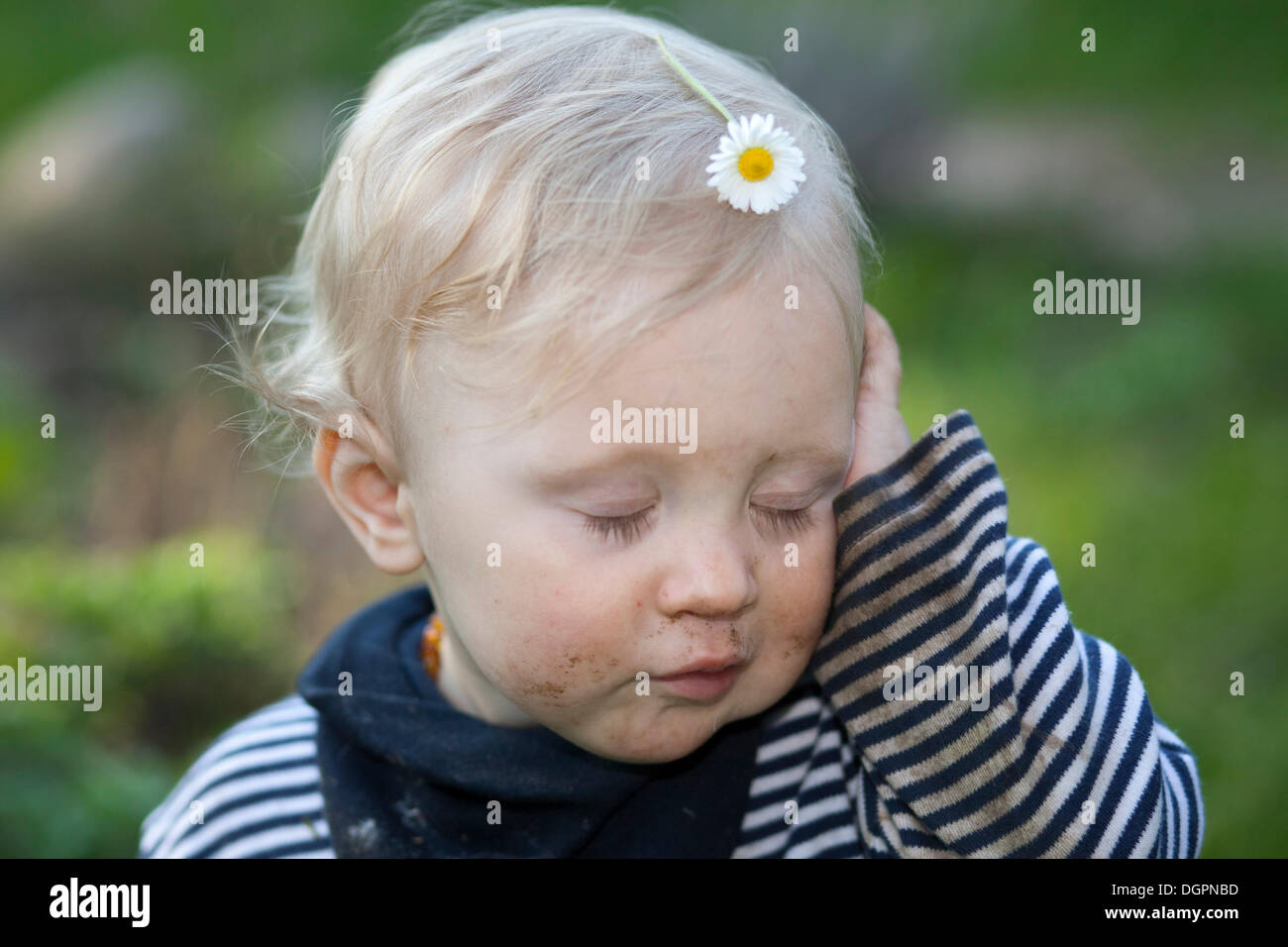 Small tired boy with a daisy on his head Stock Photo