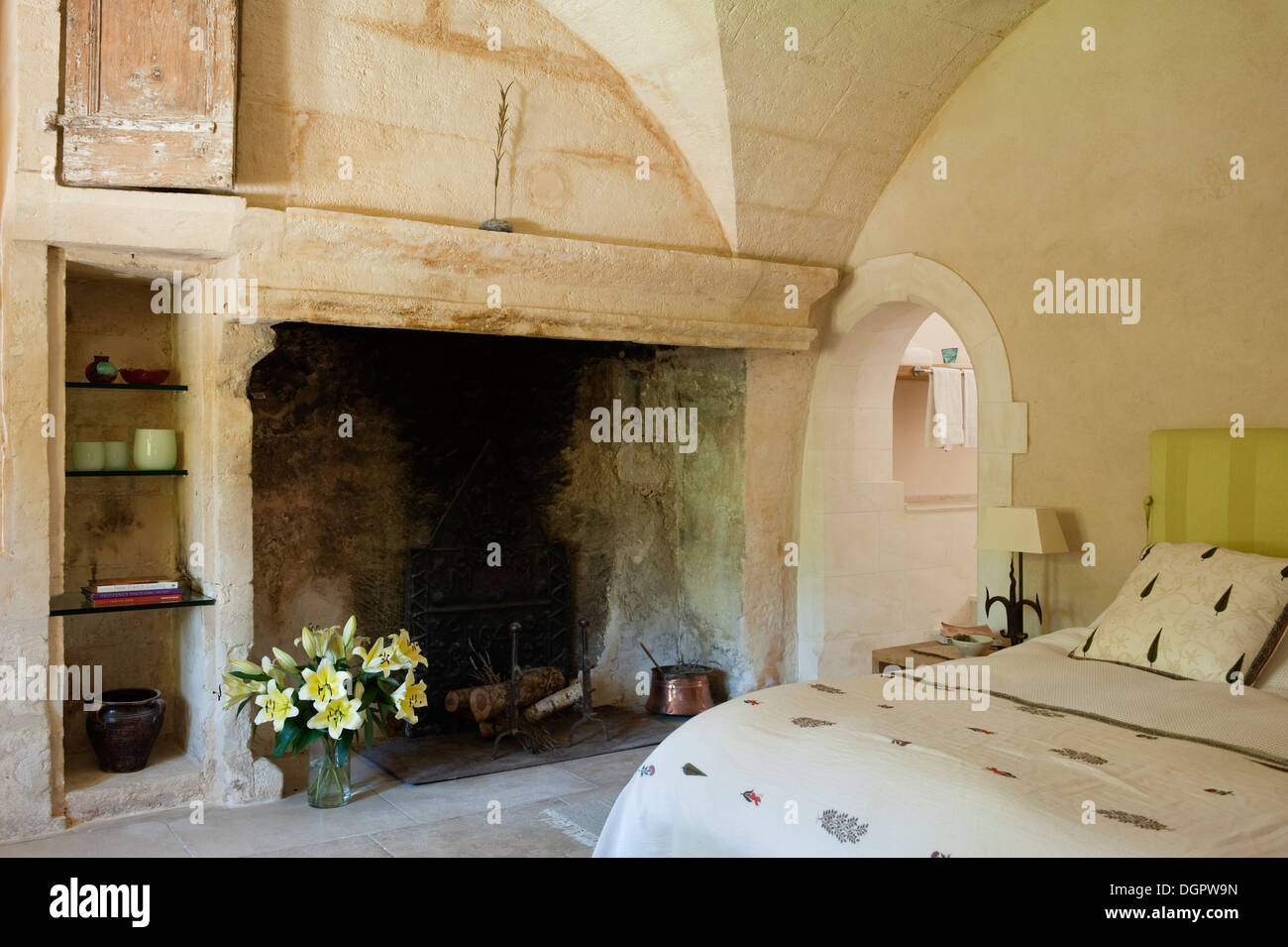 Open Stone Fireplace With Decorative Vase Of Lilies In A