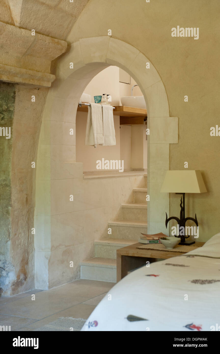 Bedroom with stone archway with steps leading to a bathroom Stock Photo