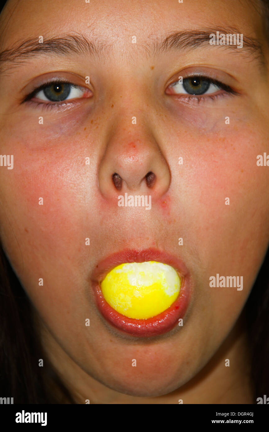 Young girl with large gobstopper sweet in her mouth Stock Photo